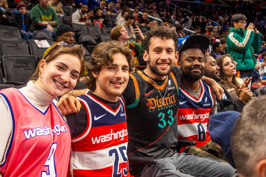 A group of enthusiastic fans poses for a photo while attending a Washington Wizards basketball game.