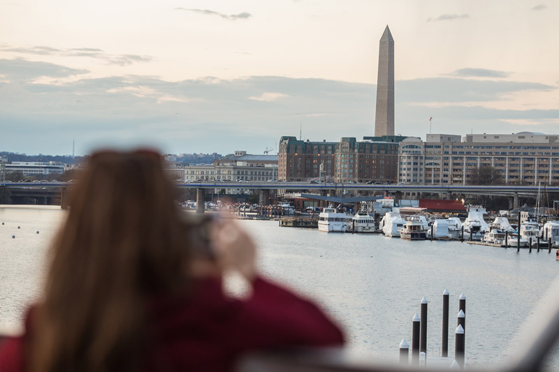 Woman taking photo of Washington Monument from Entertainment Cruises boat - Boating activities on the water in Washington, DC