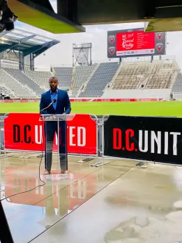 Elliott Ferguson speaking with Audi Field in the background